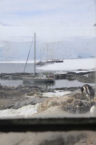Boats and Penguin through the window at Port Lockroy